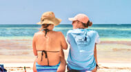 Two women sitting on the beach looking at the ocean.